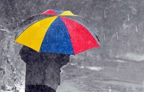 színes esernyőt tart az úr az esőben, vizes a táj, esik az eső